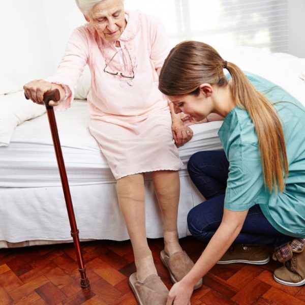 Nurse helping older woman put on shoes (Medium) - Aged Care & NDIS Newcastle - Extracare Home Services